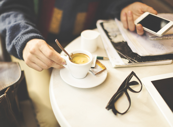 Young man drinking espresso and texting in a cafe